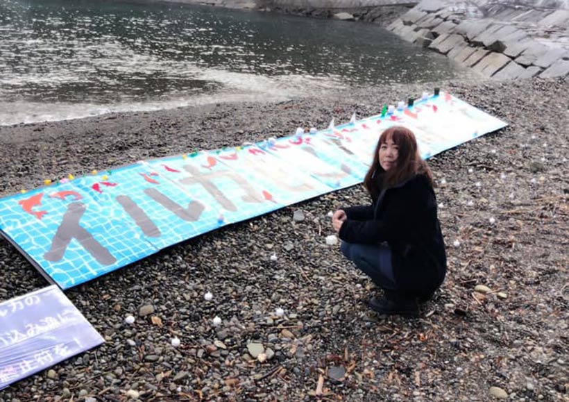 Japanische Aktivistin in der Bucht mit einer aufgespannten Plane: Stop Killing Dolphins, auf japanisch